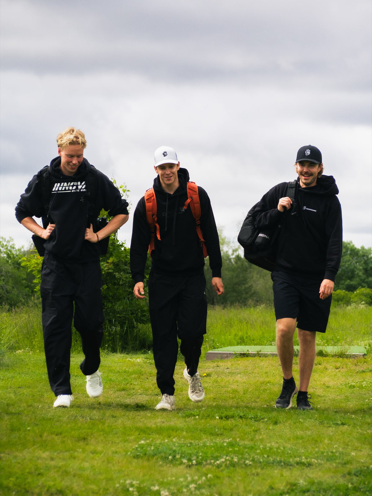Three players walking on the course with bags on their backs